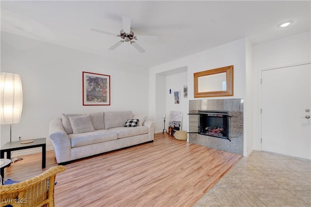 living room featuring ceiling fan, light tile patterned flooring, and a tiled fireplace