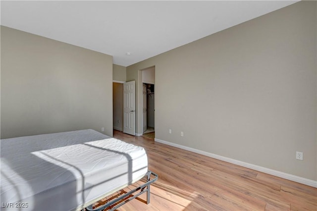 bedroom with light wood-type flooring, a closet, and a spacious closet