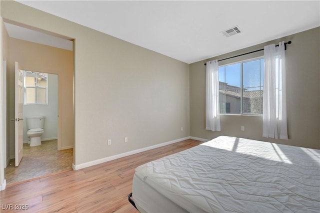 bedroom with ensuite bathroom and light hardwood / wood-style flooring