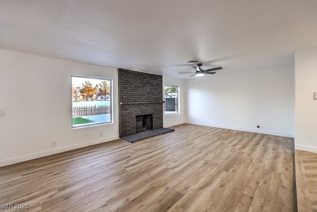 unfurnished living room with ceiling fan, light wood-type flooring, and a fireplace