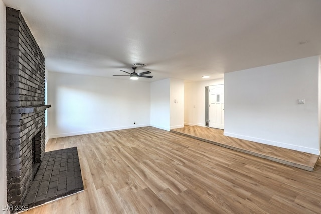 unfurnished living room with a brick fireplace, light hardwood / wood-style flooring, and ceiling fan