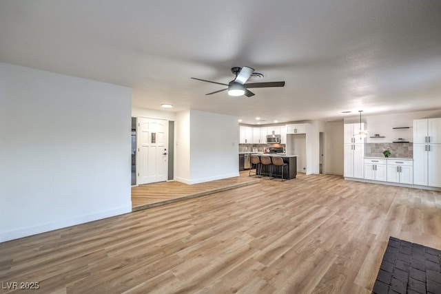 unfurnished living room with ceiling fan and light hardwood / wood-style floors