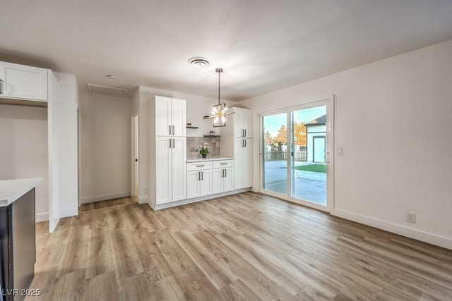 unfurnished dining area featuring an inviting chandelier and light hardwood / wood-style floors