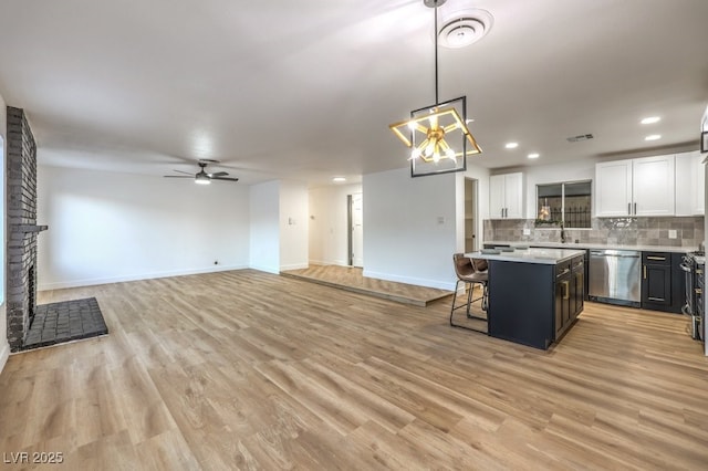 kitchen with a center island, decorative light fixtures, white cabinetry, a kitchen breakfast bar, and stainless steel dishwasher