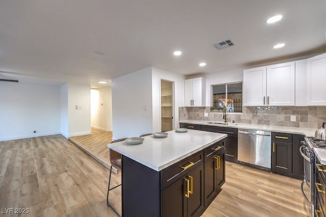 kitchen with a breakfast bar area, appliances with stainless steel finishes, decorative backsplash, white cabinets, and a center island