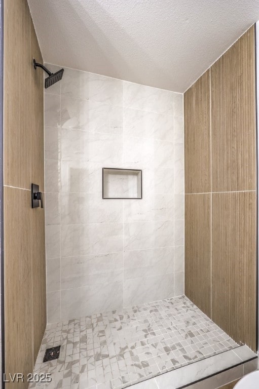 bathroom featuring a textured ceiling and tiled shower