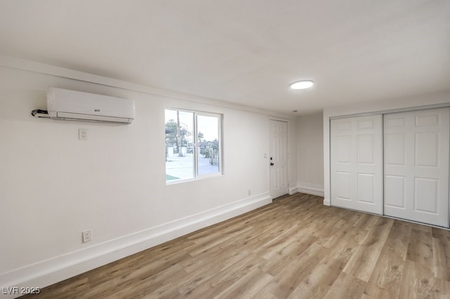 unfurnished bedroom featuring a closet, light hardwood / wood-style flooring, and a wall mounted air conditioner