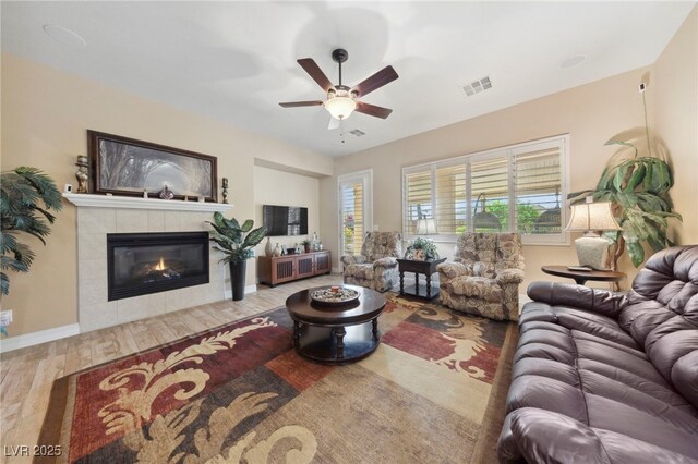 living room with hardwood / wood-style flooring, ceiling fan, and a fireplace