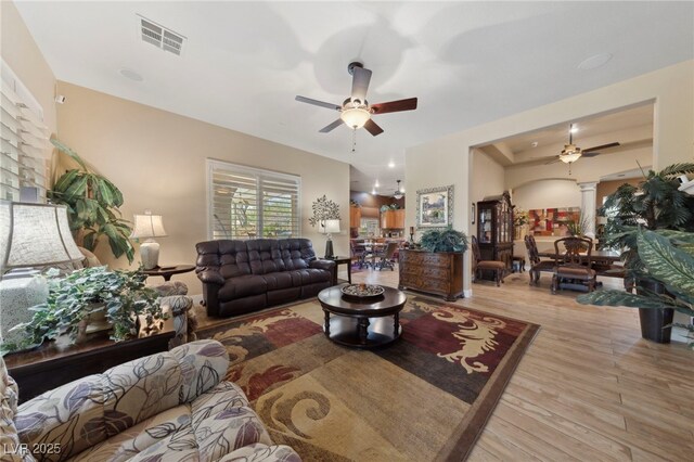 living room with ceiling fan, light hardwood / wood-style flooring, and decorative columns