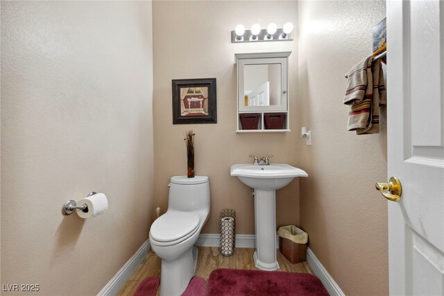 bathroom featuring toilet, hardwood / wood-style flooring, and sink