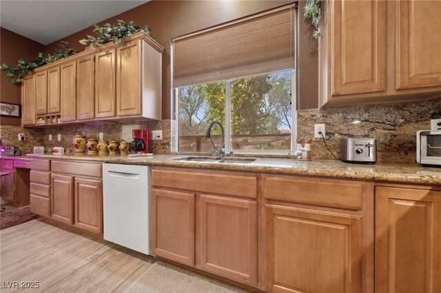 kitchen featuring dishwasher, tasteful backsplash, light hardwood / wood-style floors, sink, and light stone counters