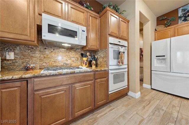 10372 Hawks Wing St, Las Vegas, NV 89178 - kitchen with tasteful backsplash, white appliances, light stone counters, and light hardwood / wood-style flooring