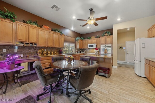 kitchen with white appliances, a kitchen island, tasteful backsplash, ceiling fan, and light hardwood / wood-style flooring