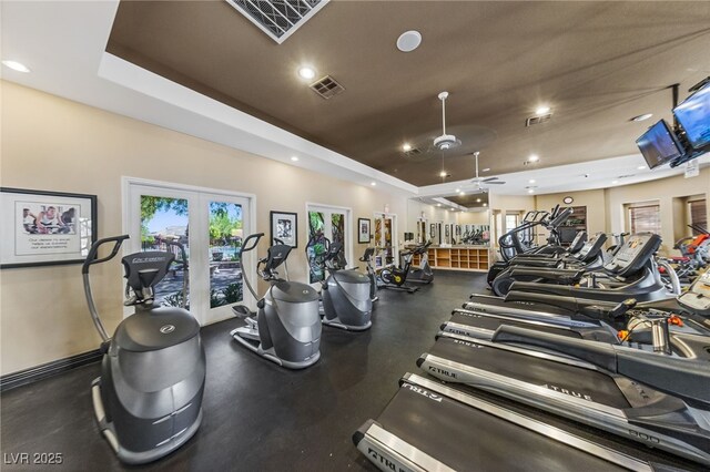 exercise room featuring ceiling fan, french doors, and a tray ceiling