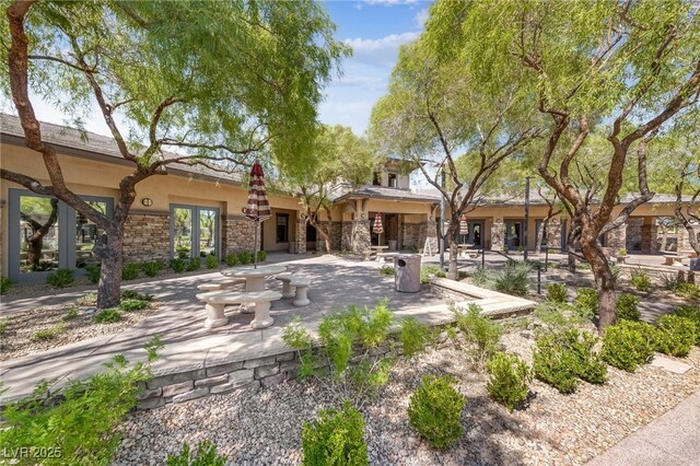 back of property with an outdoor stone fireplace and a patio