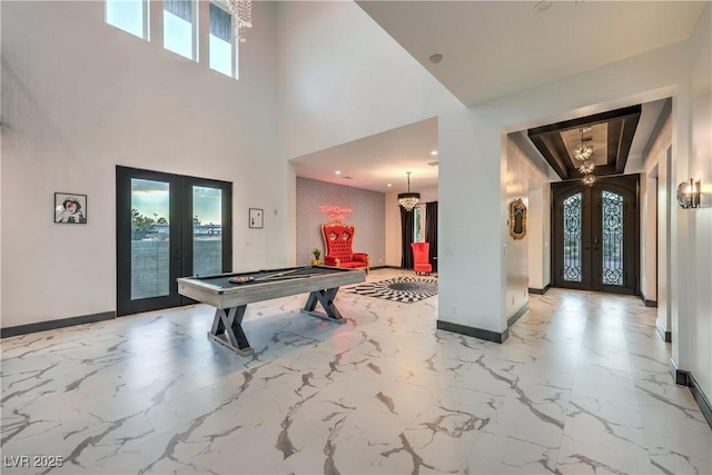 playroom with a towering ceiling, french doors, and a notable chandelier