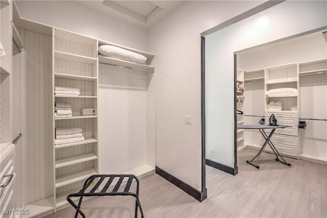 walk in closet with light hardwood / wood-style flooring