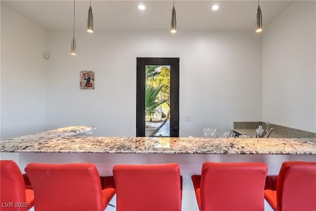 kitchen with kitchen peninsula, hanging light fixtures, and stone countertops