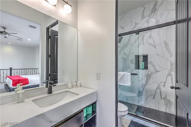 bathroom with toilet, ceiling fan, a shower with door, and vanity