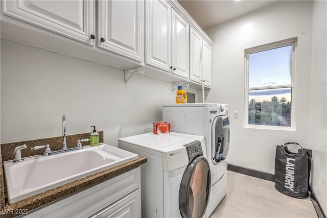 clothes washing area featuring light wood-type flooring, cabinets, washer and dryer, and sink