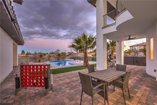 patio terrace at dusk with ceiling fan and a balcony