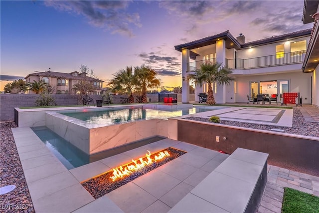 pool at dusk featuring a hot tub, a fire pit, and a patio