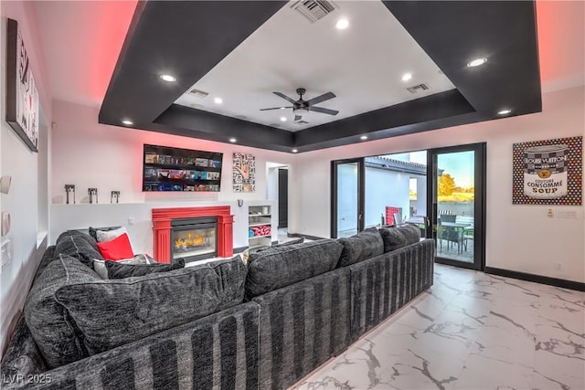 living room featuring ceiling fan and a raised ceiling