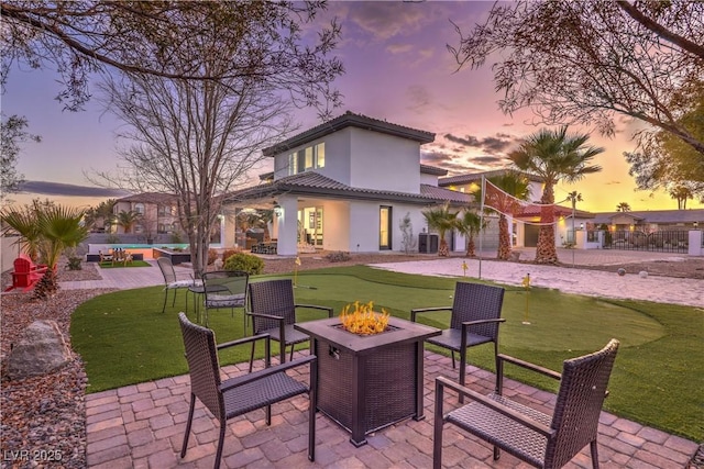 back house at dusk featuring a patio area and a fire pit