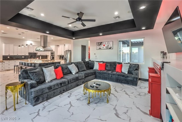 living room with ceiling fan and a tray ceiling