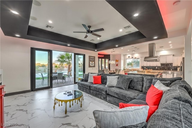 living room featuring ceiling fan and a raised ceiling