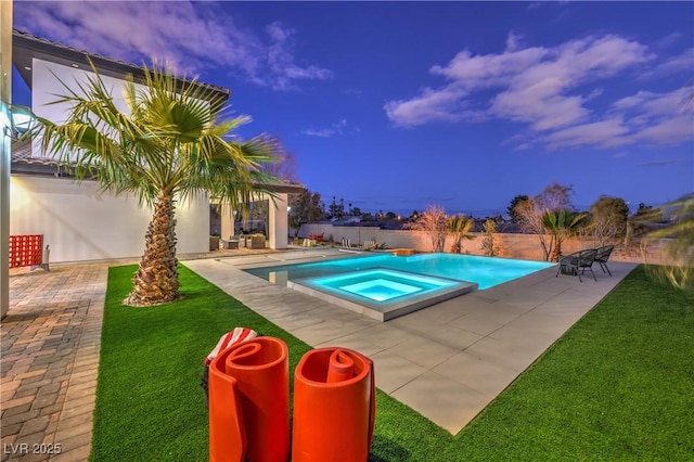 pool at dusk with an in ground hot tub, a yard, and a patio