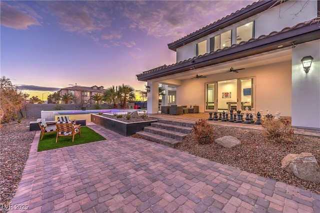 patio terrace at dusk with ceiling fan and an outdoor living space