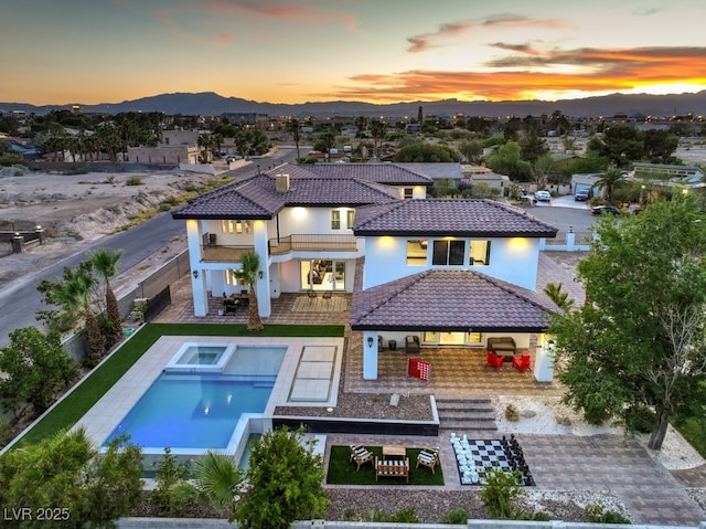 back house at dusk featuring a mountain view and a balcony