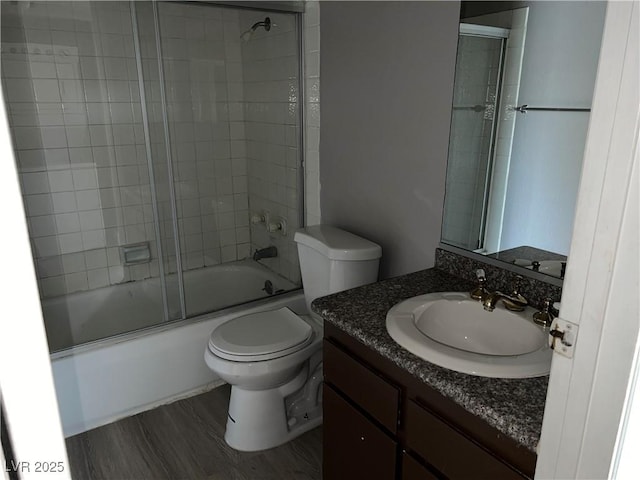 full bathroom featuring toilet, enclosed tub / shower combo, hardwood / wood-style floors, and vanity