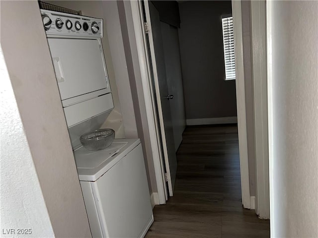 clothes washing area featuring dark hardwood / wood-style floors and stacked washer and clothes dryer