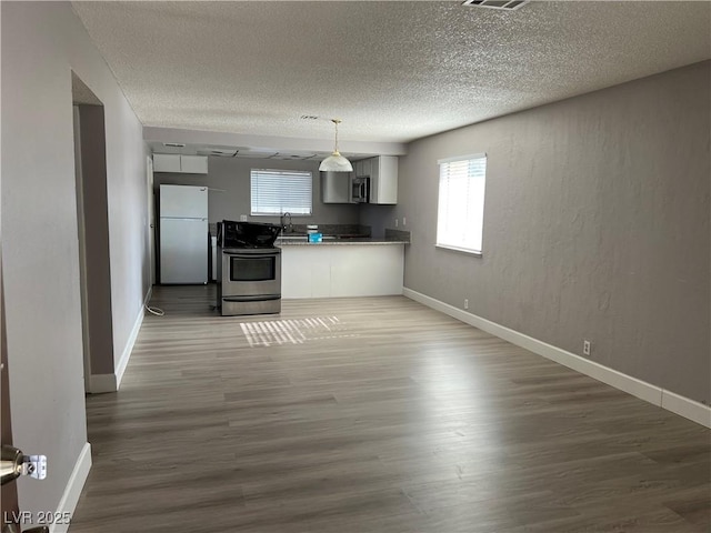 kitchen featuring pendant lighting, wood-type flooring, sink, white cabinetry, and stainless steel appliances