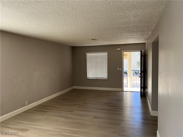 empty room featuring a textured ceiling and hardwood / wood-style flooring