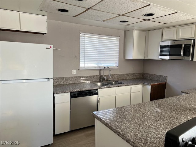 kitchen with sink, white cabinetry, appliances with stainless steel finishes, and light wood-type flooring