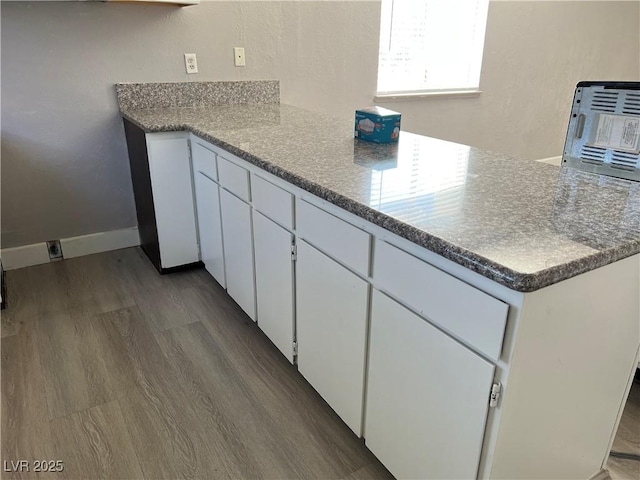 kitchen featuring wood-type flooring and white cabinetry