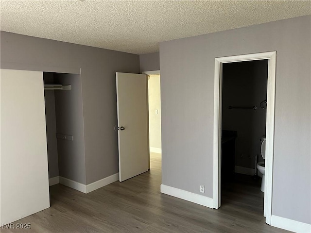 unfurnished bedroom with a textured ceiling, a closet, and dark hardwood / wood-style flooring