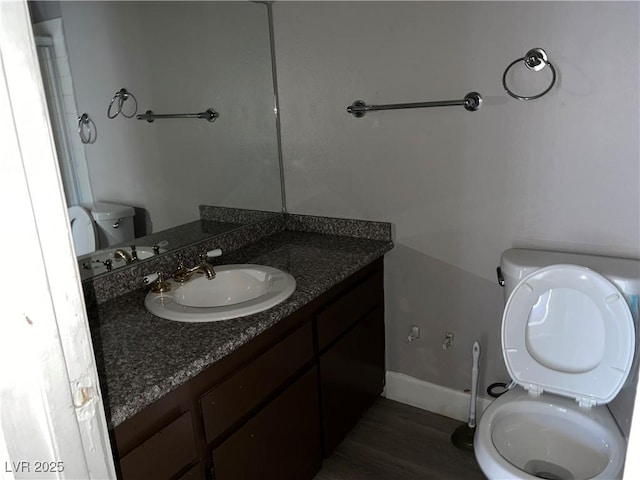 bathroom with toilet, vanity, and wood-type flooring