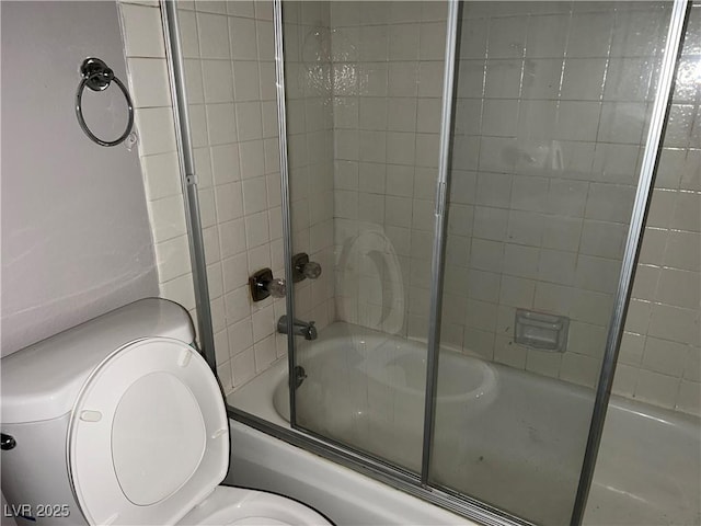 bathroom featuring toilet and combined bath / shower with glass door