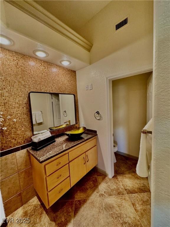 bathroom featuring toilet, ornamental molding, and vanity