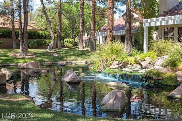 view of community featuring a garden pond and a pergola