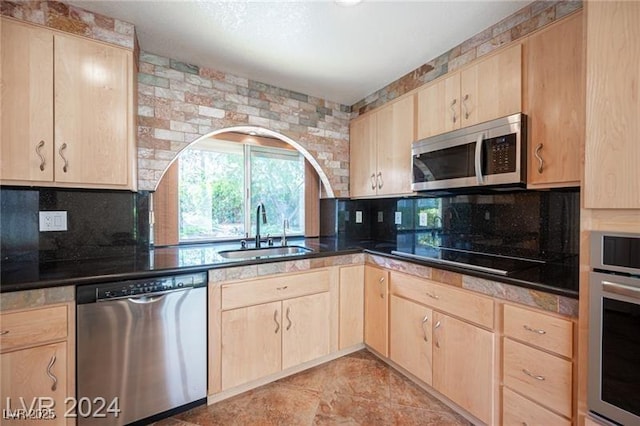 kitchen featuring appliances with stainless steel finishes, light brown cabinetry, and sink