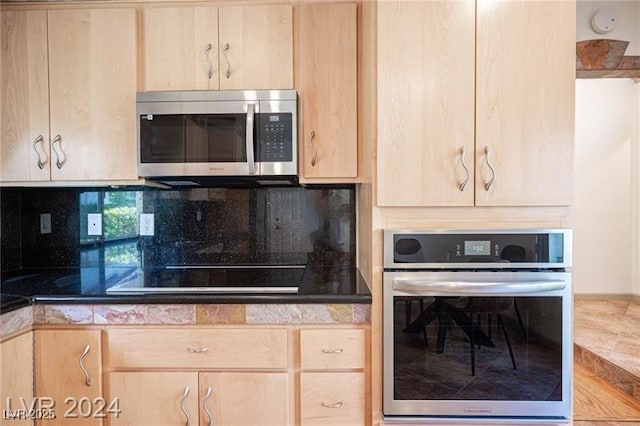 kitchen with light brown cabinetry, backsplash, and appliances with stainless steel finishes