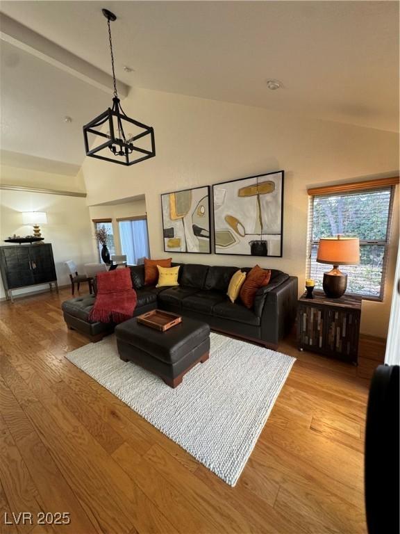 living room with lofted ceiling, wood-type flooring, and a notable chandelier