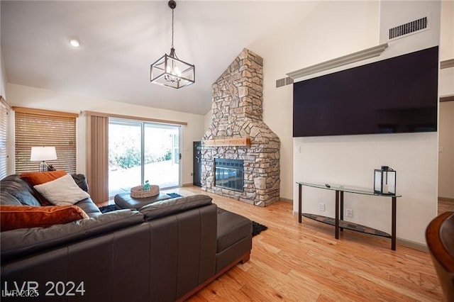 living room featuring lofted ceiling, light wood-type flooring, a fireplace, and a chandelier