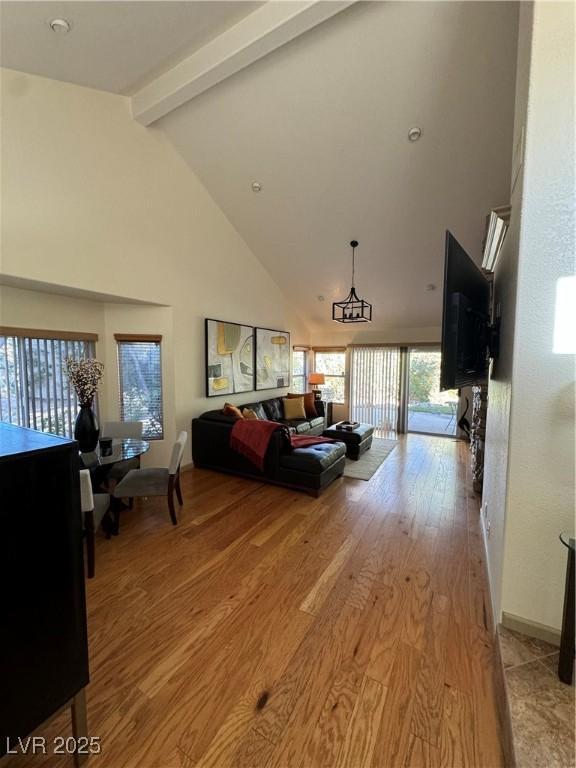 living room with beam ceiling, high vaulted ceiling, and light hardwood / wood-style flooring