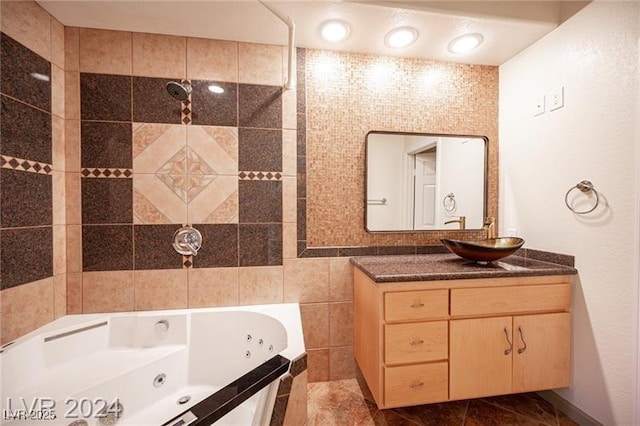 bathroom featuring tile walls, tile patterned floors, tiled tub, and vanity